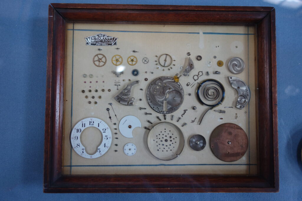 Picture framing containing a disassembled pocket watch.